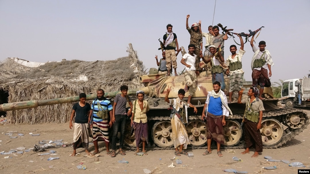FILE - Tribal fighters loyal to the Yemeni government stand by a tank in al-Faza area near Hodeida, Yemen, June 1, 2018.