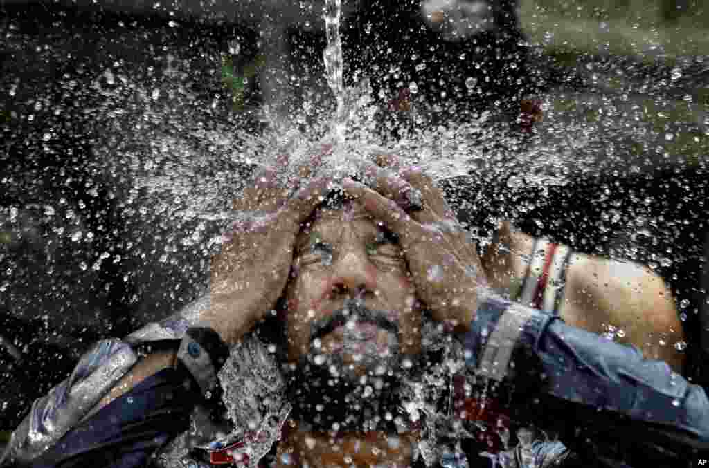 Seorang pria mendinginkan diri dengan air di siang hari yang panas pada bulan Ramadan, di Islamabad, Pakistan.