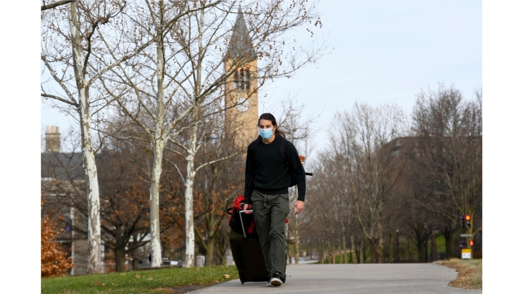 Cornell University sophomore, Kieran Adams, wheels his luggage through the university's campus in Ithaca, NY, Dec. 16, 2021, en route to go home after the university abruptly shut down all campus activities.