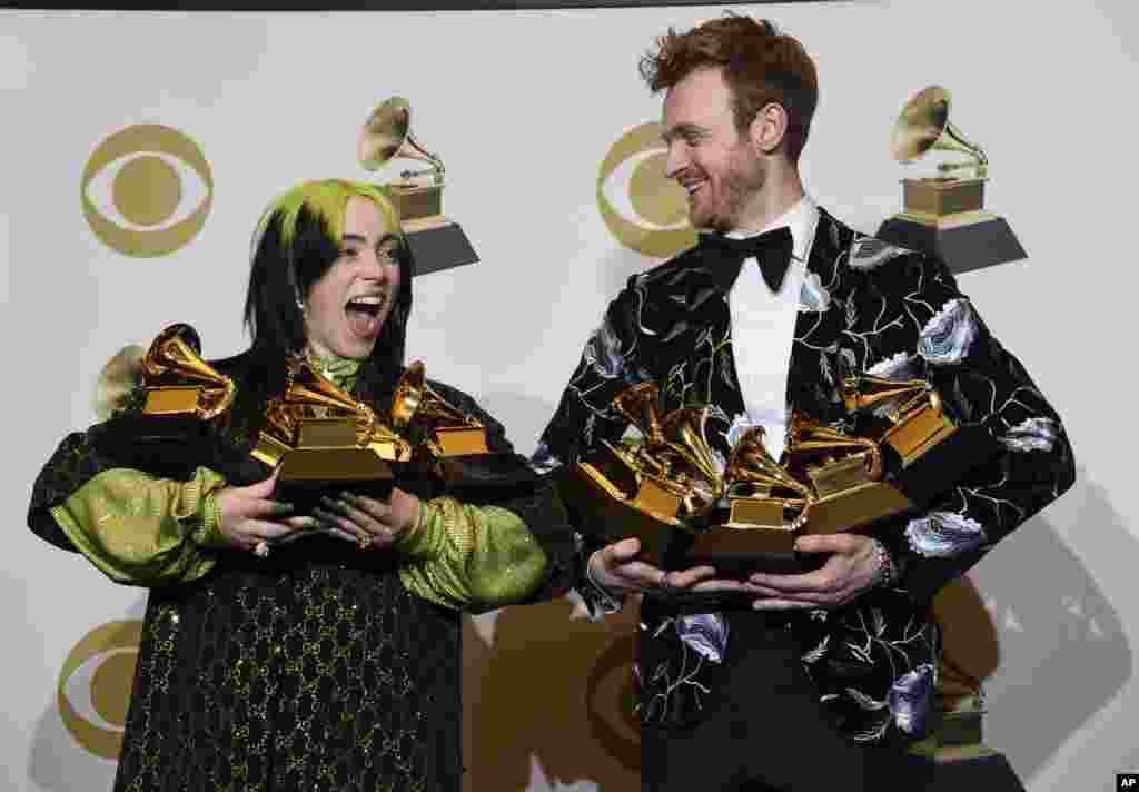Billie Eilish, left, and Finneas O'Connell pose in the press room with the awards for best album, best engineered album and best pop vocal album for "We All Fall Asleep, Where Do We Go?," best song and record for "Bad Guy," best new artist and best producer, non-classical at the 62nd annual Grammy Awards at the Staples Center in Los Angeles, Jan. 26, 2020.