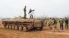 Rebel fighters walk past an armored vehicle carrying the flag of the Tahrir al-Sham rebel alliance near the town of Maardes in the countryside of the central Syrian province of Hama, March 22, 2017. Tahrir al-Sham, an al-Qaida offshoot, has recently emerged as the most powerful Sunni insurgent faction in Syria after consolidating its control over most of the northwestern province of Idlib.