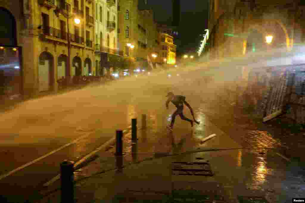 A demonstrator is hit by a water cannon during a protest against a ruling elite accused of steering Lebanon towards economic crisis in Beirut.