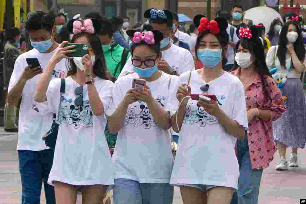 Visitors, wearing face masks, enter the Disneyland theme park in Shanghai, China.