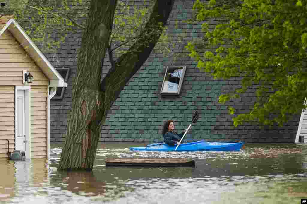 A woman use a kayak to assess the damage at homes in her neighborhood on Oakridge Road on Wixom Lake in Beaverton, Michigan. Rapidly rising water has overtaken dams and forced the evacuation of about 10,000 people from flooded communities in central Michigan. (Credit: Midland Daily News) 