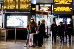 Travelers wear face masks as they wait at the Termini train station in Rome, March 8, 2020.