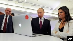 Russian President Vladimir Putin and Editor-in-chief of RT, 24-hour English-language TV news channel, Margarita Simonyan, attend an exhibition marking RT's 10th anniversary in Moscow, Russia, Thursday, Dec. 10, 2015. (Mikhail Klimentyev/Sputnik, Kremlin Pool Photo via AP)