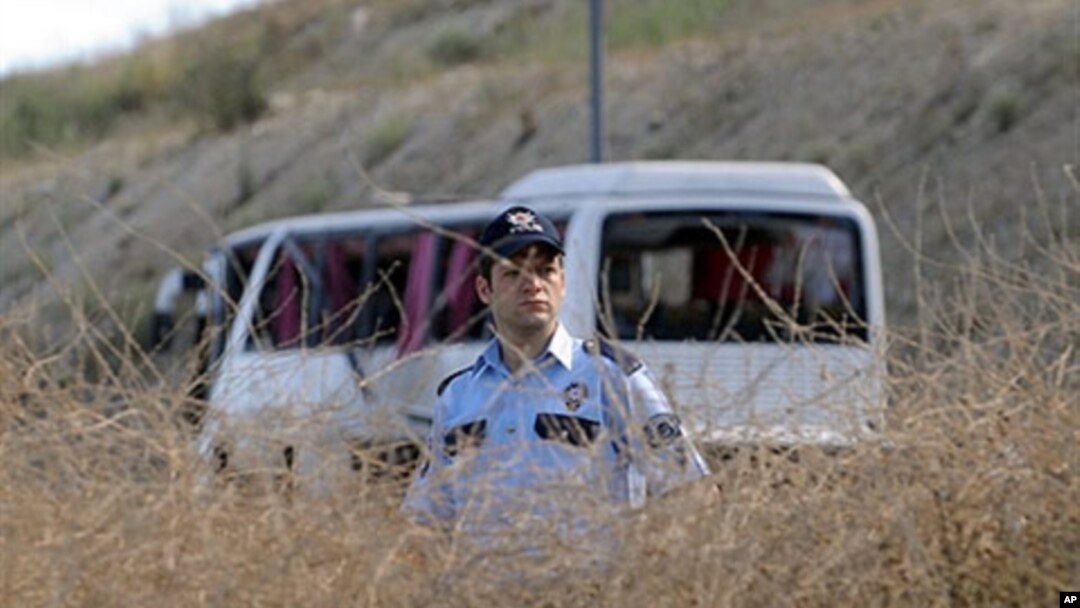 A police officer stands in front of the wreckage of a military bus after a roadside bomb blew up the bus in Istanbul, 22 Jun 2010