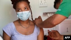 A woman is vaccinated by a member of the Western Cape Metro EMS in an ambulance at a COVID-19 vaccination event in Manenberg, in Cape Town, Dec. 8, 2021.
