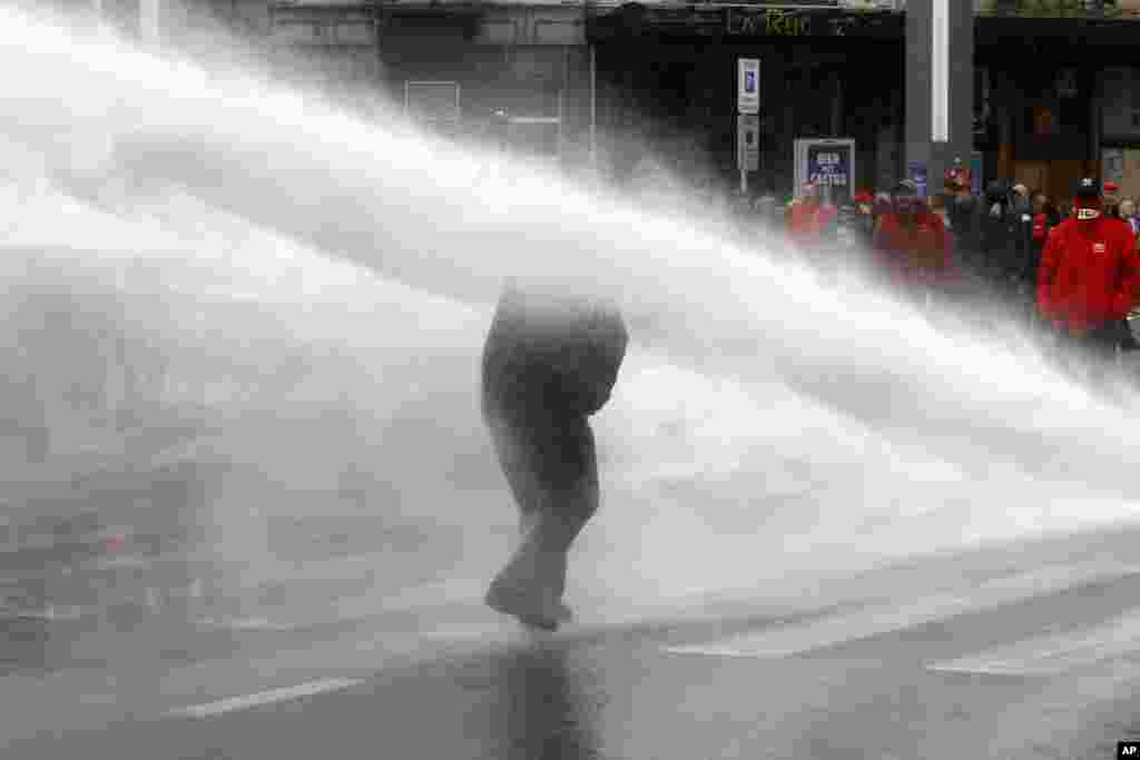Seorang demonstran terkena tembakan meriam air polisi anti huru-hara pada aksi unjuk rasa di Brussels, Belgia.