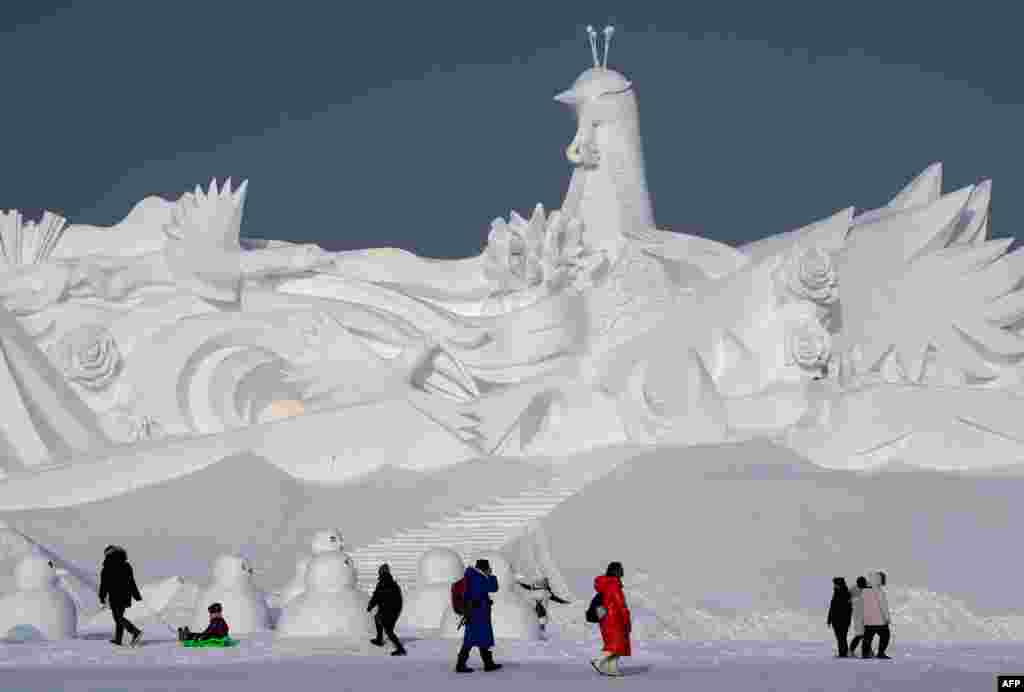 Tourists walk in front of an ice sculpture ahead of the opening of the Harbin International Snow and Sculpture Festival in Harbin, in China's northeast Heilongjiang province, Jan. 4, 2020.