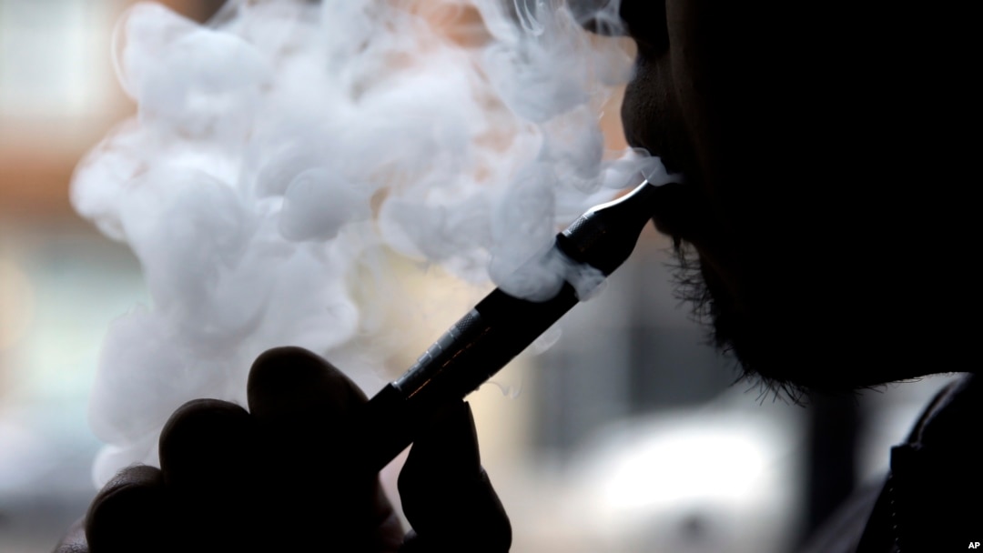 FILE - A smoker demonstrates an e-cigarette at Vape store in Chicago, April 23, 2014. A new study found that toxicity levels of e-cigarettes can fluctuate with the temperature, type and age of the device, a new study has found.
