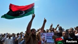 Men hold up a picture of slain lawyer and prominent Libyan activist Abdelsalam al-Mosmary, during his funeral in Benghazi, July 27, 2013.