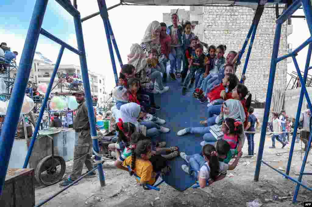 Children play at a makeshift amusement park as they celebrate the Eid al-Fitr feast in Syria's northwestern city of Idlib.