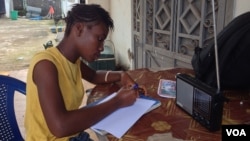 17-year- old Doris Ansumana listening to a radio school program in Freetown, Sierra Leone, October 20, 2014. (N.deVries/VOA).