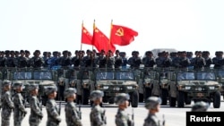 中國解放軍軍人在內蒙古朱日和訓練基地參加閱兵，慶祝解放軍建軍90週年。中共黨旗在前，國旗居中，軍旗在後（2017年7月30日）