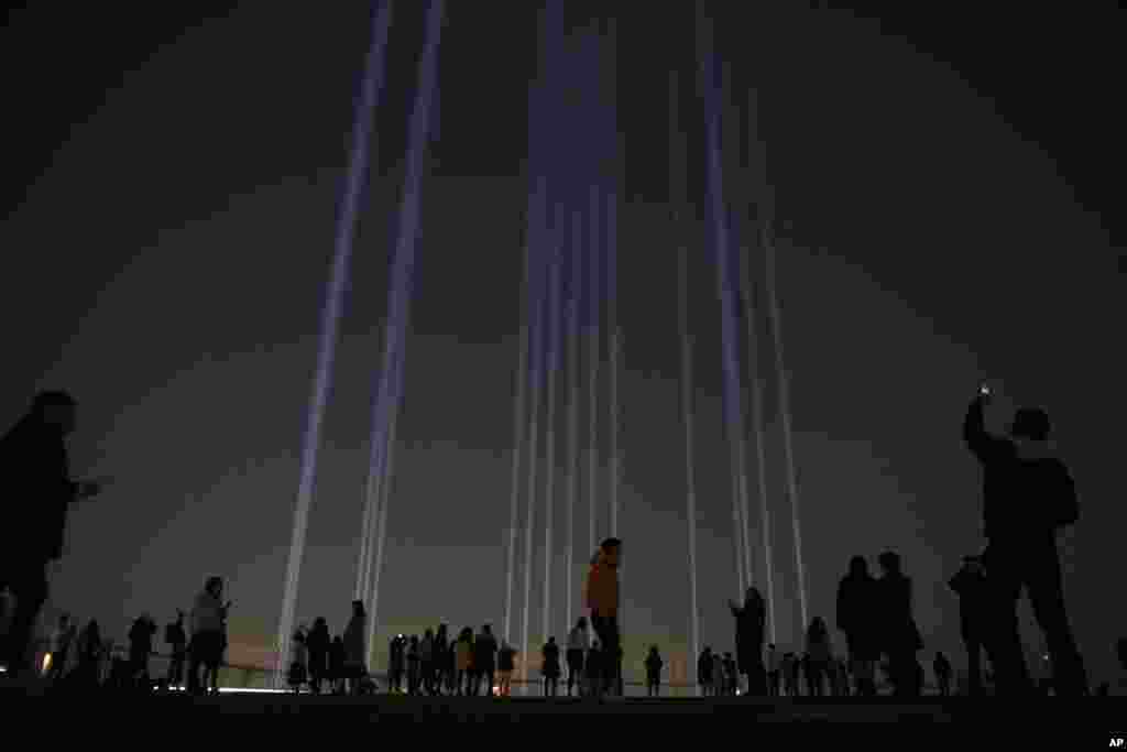 People take pictures of a light show called "Crossing Light" at Shibuya Sky observation deck in the Shibuya district of Tokyo, Japan.