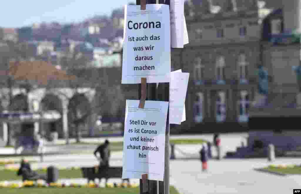 Signs reading "Corona is also what we do out of it" (top) and "Imagine this is Corona and nobody looks at it panickly" are seen on a pole in Stuttgart, southern Germany.