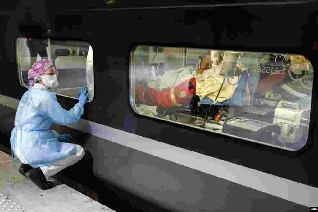 A medical staff watches from a platform of the Gare d'Austerlitz train station in Paris, France, through the window of a medicalized TGV high speed train before its departure to evacuate patients infected with the COVID-19 from Paris' region hospital to other hospitals in Brittany region.