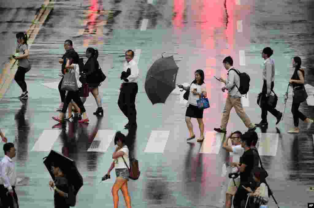 A woman struggles with her umbrella in strong winds and rain from approaching Typhoon Matmo in Taipei, July 22, 2014.