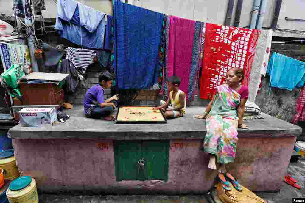 Dua anak bermain karambol di kawasan permukiman kumuh di Kolkata, India.