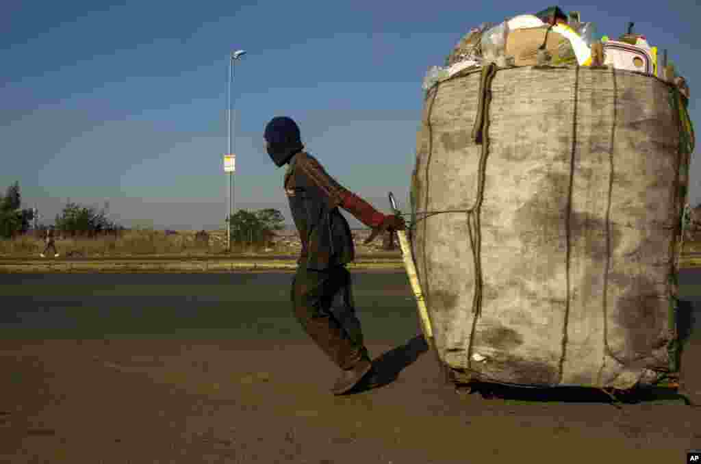 A man pulls a trolley filled with cardboard and plastic bottles for recycling on a street in Phumlamqashi informal settlement near Johannesburg, South Africa.