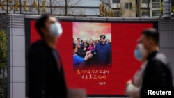 上海街頭戴著口罩的行人走過宣傳習近平的宣傳畫。 （2020年3月23日）