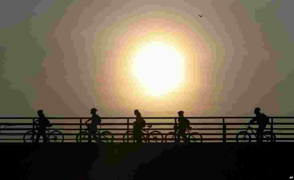 Commuters walk their bicycles across a pedestrian bridge, in Bogota, Colombia.