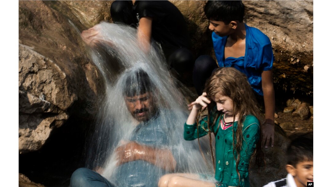FILE - A family cools off in a stream during a heat wave, in Islamabad, Pakistan, May 30, 2017. The town of Turbat in southwestern Pakistan reported a temperature of 54 degrees Celsius in May.