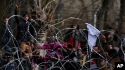Migrants stand behind a fence near the Kastanies border gate at the Greek-Turkish border, March 2, 2020.