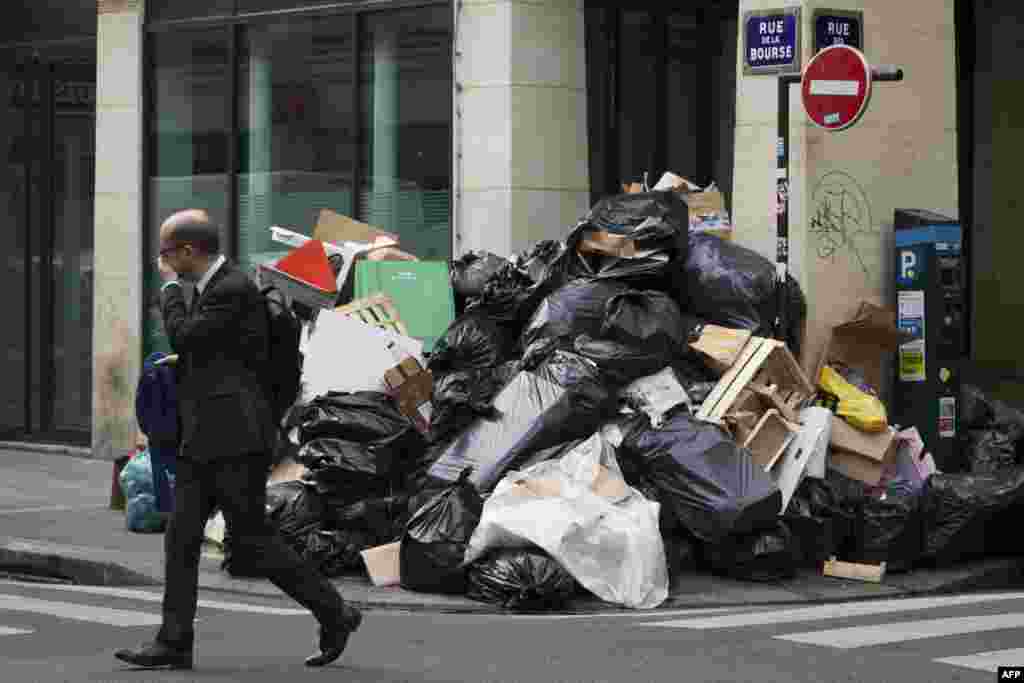 A man walks past a pile of un-collected rubbish in Paris, France. Paris Mayor Anne Hidalgo promised that rubbish piling up in the city due to an ongoing strike would be collected, as fans arrive for the Euro 2016 football championships.