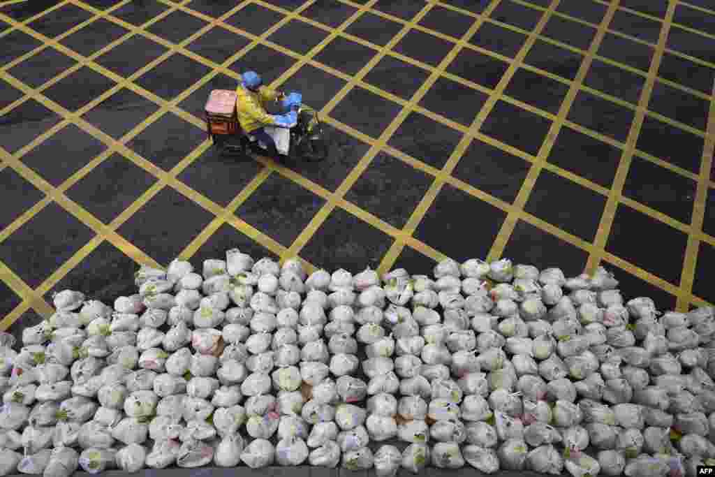 A man rides past bags of vegetables being prepared for delivery on an almost empty street in Wuhan, in China's central Hubei province.