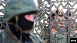 Ukraine - Armed man in military uniform, believed to be Russian, stands outside the territory of the Ukrainian naval headquarters as Ukrainian troops guard their base in Sevastopol, 03 March 2014. 