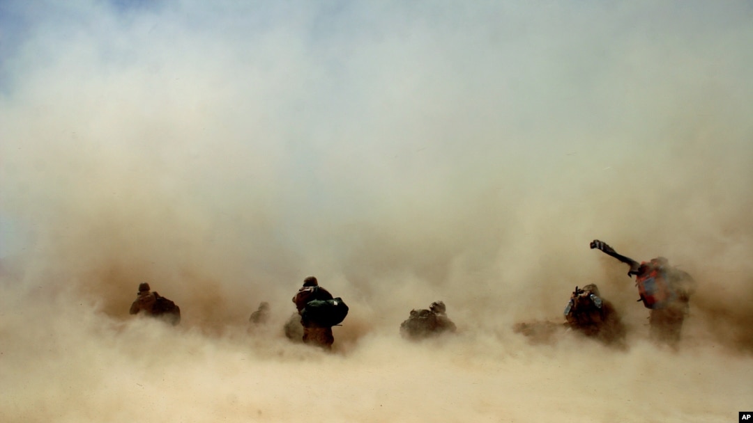 FILE - U.S. soldiers and their Afghan translators shelter from dust kicked up by a Chinook helicopter as it takes off from Mangal Khan village, Khakeran Valley, Zabul province, Afghanistan, June 2005.