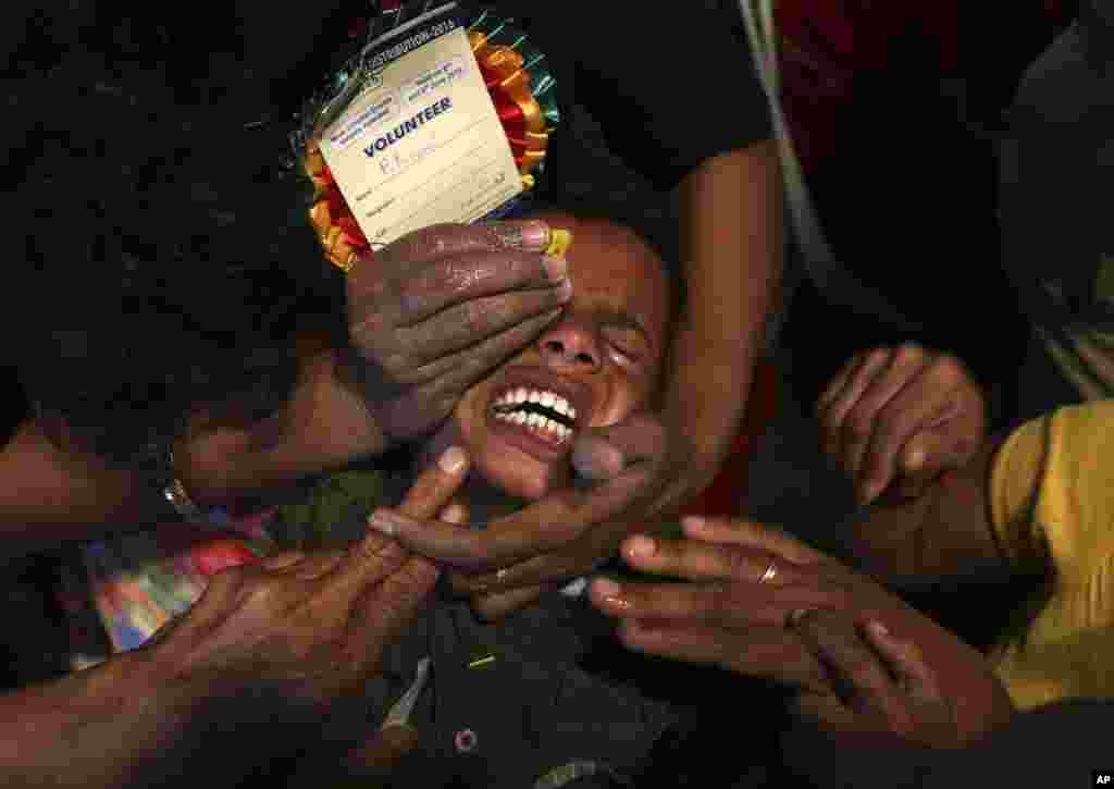 Para relawan berusaha membuka mulut seorang anak yang menderita asma untuk memasukkan obat tradisional di Hyderabad, India.