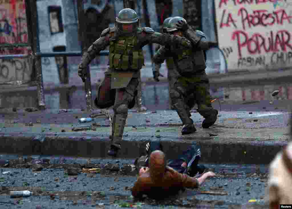 Riot police officers clash with demonstrators during protests against Chile's government in Santiago, Dec. 14, 2019.