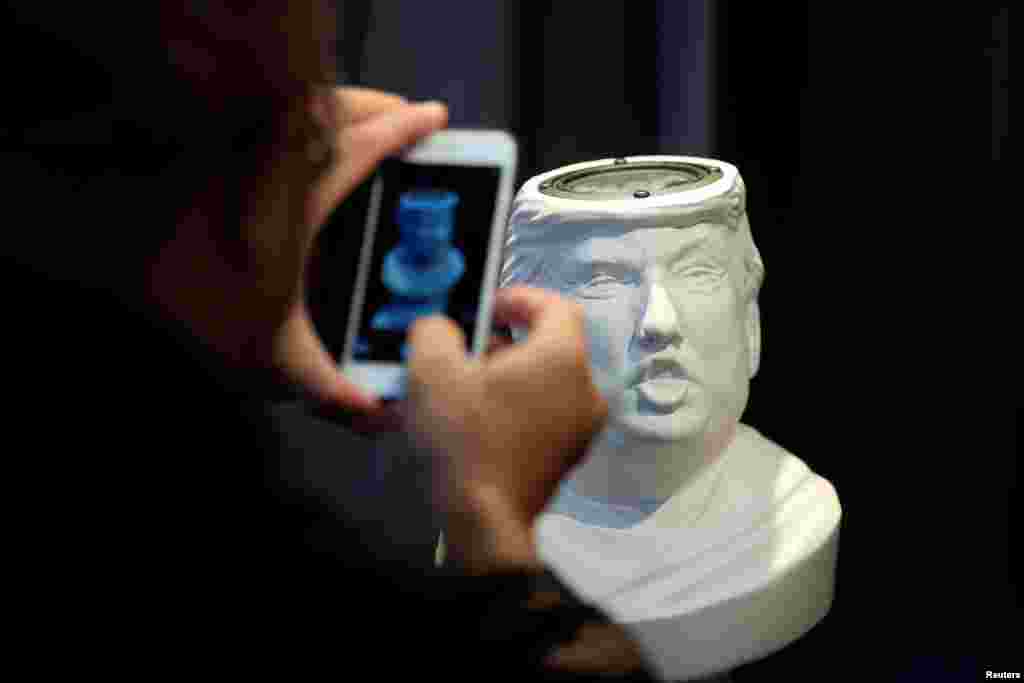 Seorang pria memotret pengeras suara Sound Of Power berbentuk patung Donald Trump yang dipasang di CES (Consumer Electronics Show) Asia 2016 di Shanghai, China.