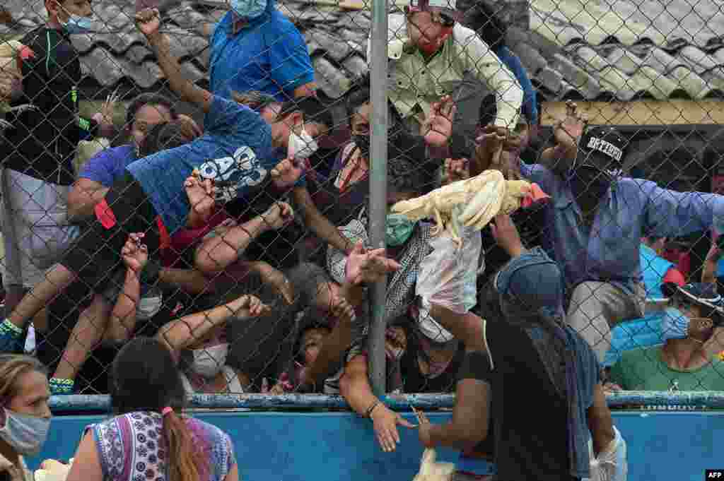 People crowd to receive hens given by Honduran presidential pre-candidate for LIBRE party, Wilfredo Mendez, in the working-class neighborhood of El Carrizal, in Tegucigalpa, amid the new coronavirus pandemic.