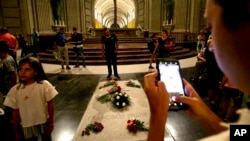 FILE - People stand around the tomb of late Spanish dictator Francisco Franco, inside the basilica at the Valley of the Fallen monument, near El Escorial, outside Madrid, Spain, Aug. 24, 2018. 