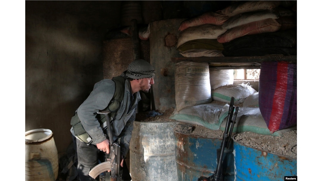 A rebel fighter looks out through sandbags on the forth day of the truce, on al-Rayhan village front near the rebel held besieged city of Douma, in the eastern Damascus suburb of Ghouta, Syria, Jan. 2, 2017.