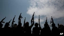 FILE - In this Aug. 22, 2020 file photo, tribesmen loyal to Houthi rebels raise their weapons in Sanaa, Yemen.