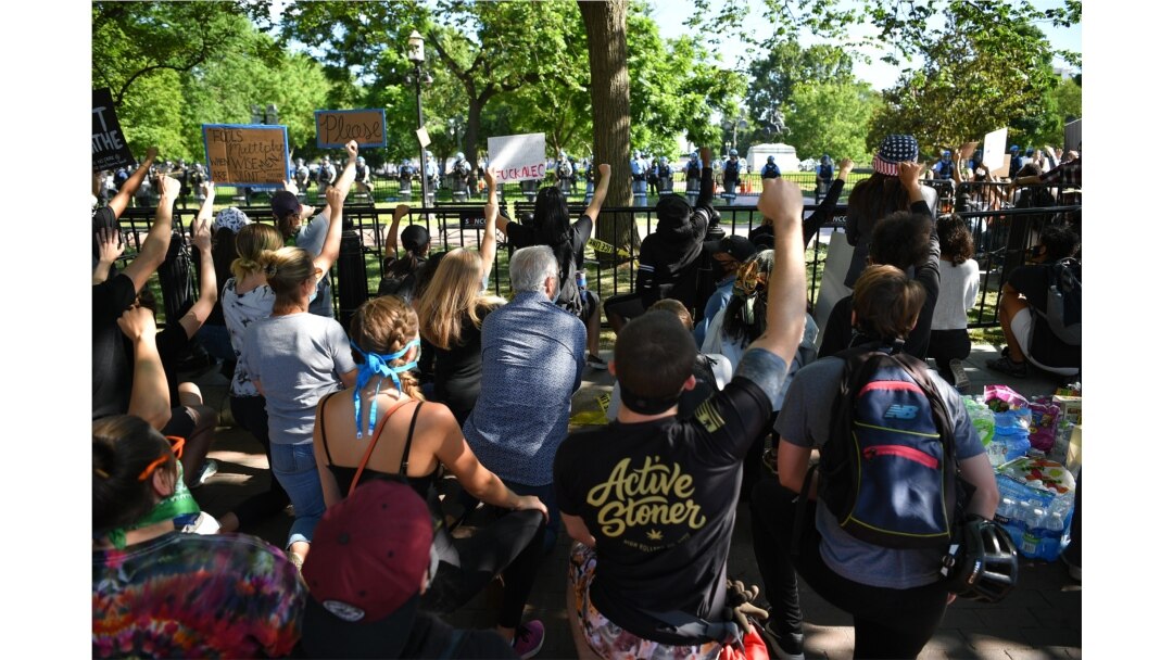 Protestors take a knee and raise their fists in Lafayette Square near the White House in Washington, DC on June 1, 2020.