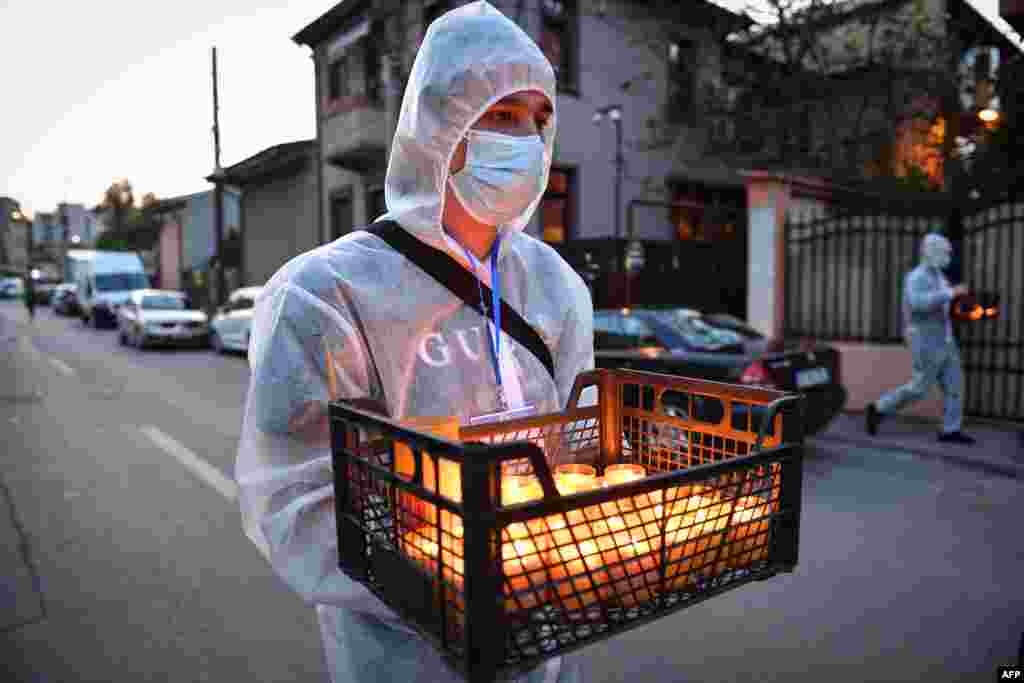 A church volunteer wearing protective equipment delivers holy candles during Christian Orthodox Easter celebration in Bucharest, Romania, April 18, 2020.
