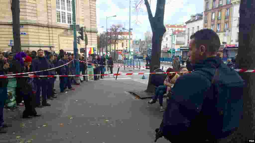 Une foule regarde la police déployée lors de l’assaut contre des personnes présumées liées aux attaques meurtrières dans la capitale française, à Saint-Denis.