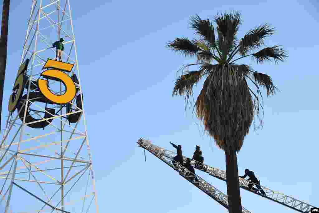 Anggota kepolisian Los Angeles (Kanan) memanjat dua tangga pemadam kebakaran untuk meraih seorang pria yang memanjat menara radio bersejarah KTLA di Hollywood, California, 11 Mei 2016. Selama hampir tiga jam seorang pria mencengkaram kuda-kuda dari menara setinggi 160 kaki (53 meter) yang terletak di Sunset Bronson Studios sebelum diturunkan dengan selamat. Pria tersebut kemudian ditahan polisi untuk keperluan evaluasi kejiwaan.