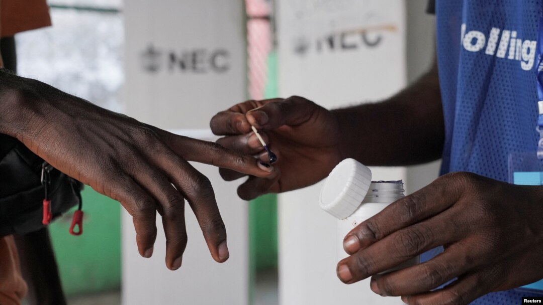 A National Elections Commission official puts indelible ink on the finger of a voter at a polling station during a runoff election between Liberian President George Weah and former Vice President Joseph Boakai, in Monrovia, Liberia, on Nov. 14, 2023.
