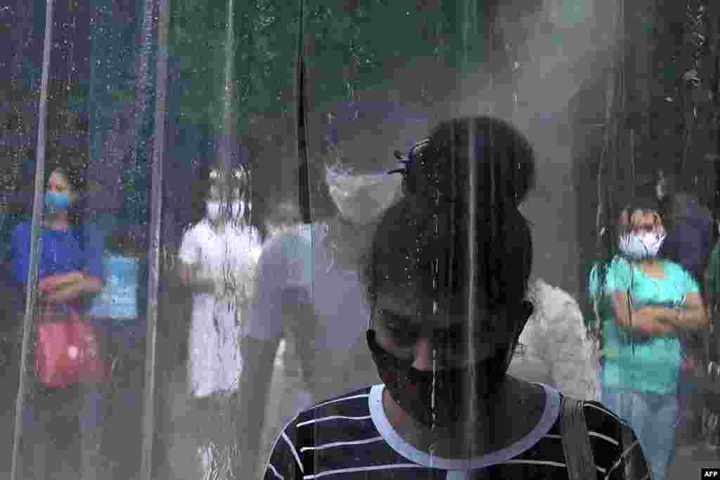 An office worker stands inside a makeshift sanitization booth before entering an office building in Colombo, Sri Lanka, as authorities eased the 24-hour curfew as a preventive measure against the spread of the COVID-19 coronavirus after 67 days.