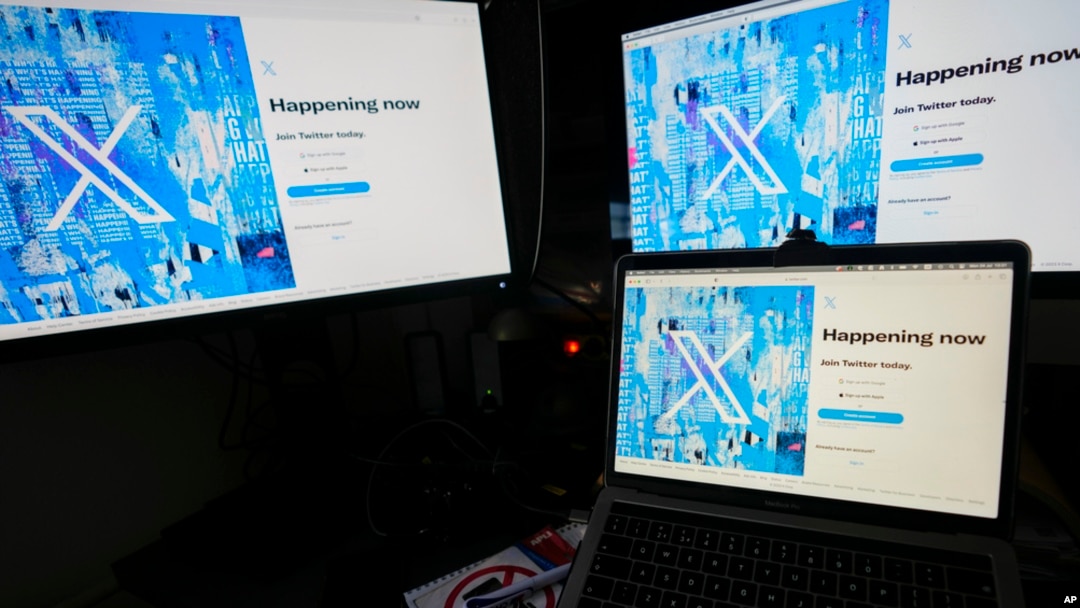 FILE - Computer monitors and a laptop display the X sign-in page, July 24, 2023.