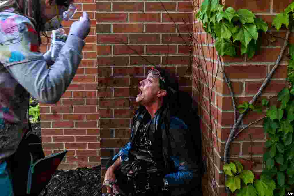 A medic protester assists a member of the media in Minneapolis, Minnesota, after police started firing tear gas and rubber bullets during a demonstration to call for justice for George Floyd, a African American man who died in police custody.