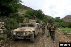FILE - Afghan Special Forces patrol at the site where a MOAB, or ''mother of all bombs," was dropped on the Achin district of the eastern province of Nangarhar, Afghanistan, April 23, 2017.
