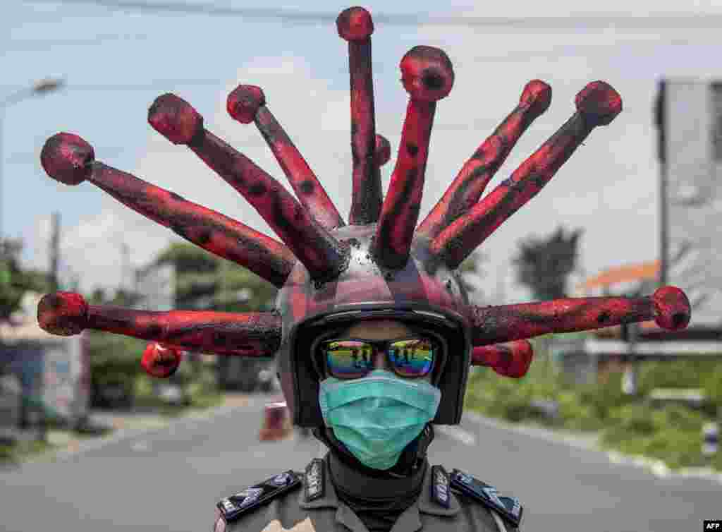 An Indonesian police officer wearing a COVID-19 coronavirus themed helmet conducts a campaign and disinfects motorists' vehicles in Mojokerto, East Java.